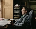 Alan Bennett sitting at a desk by a window