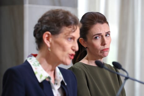 Ardern watches with a serious expression as Kitteridge speaks into a microphone at a press conference