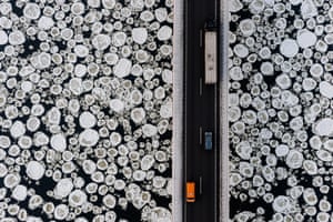 Toxic Beauty #20: a lorry and cars pass an ice-covered river