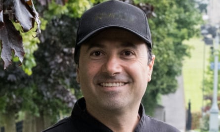 Smiling man wearing black baseball cap.