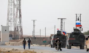 Military vehicles fly Russian and Syrian national flags near the town of Manbij on Tuesday.