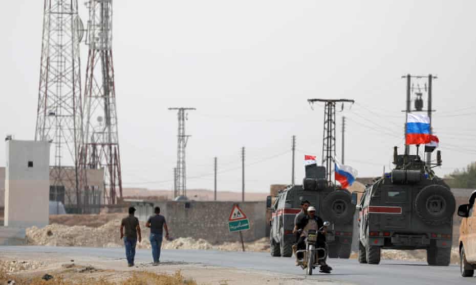 Military vehicles fly Russian and Syrian national flags near the town of Manbij on Tuesday.