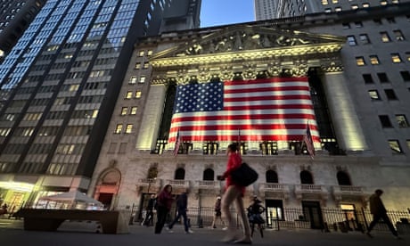La gente pasa frente a la Bolsa de Valores de Nueva York con una bandera estadounidense en ella.