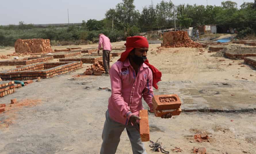Workers construct new platforms to cremate bodies outside a crematorium, in New Delhi