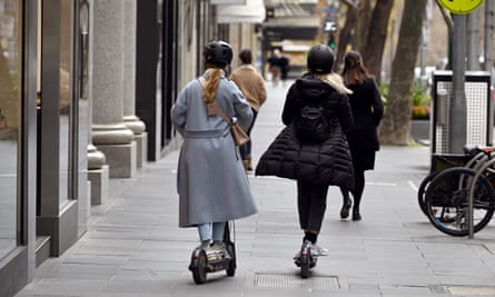 Two shoppers on e-scooters make their way down Collins Street in Melbourne