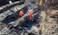 Workers dig down on to a burst pipe surrounded by mud
