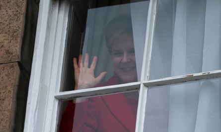 Nicola Sturgeon waves from a window, after holding a press conference resigning after eight years as first minister