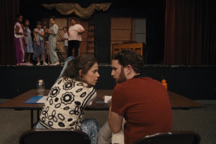 A man and a woman sitting at a desk in a theatre