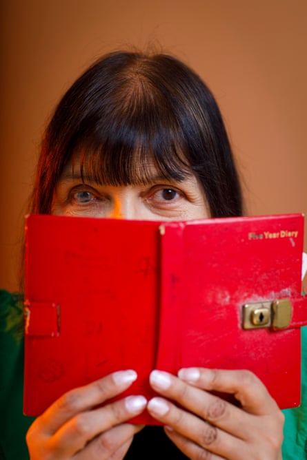 A woman holding a red diary in front of her face