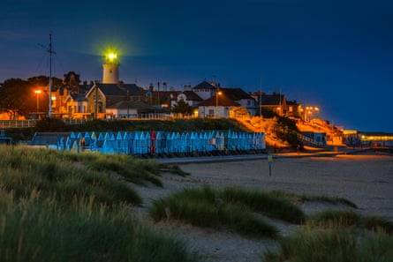 Lighthouse over beach huts and beach at night