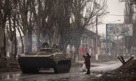 A resident waves to members of the Ukrainian military driving an armoured vehicle in Bakhmut.