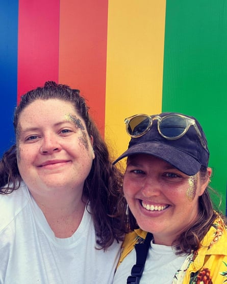 Gemma and Nic pose in front of a rainbow background