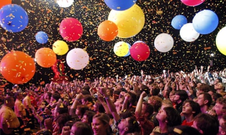 Festivalgoers at a gig in Katowice, Poland, as part of the OFF festival. Colourful balloons hover above the crowd, with ticker tape showering down.