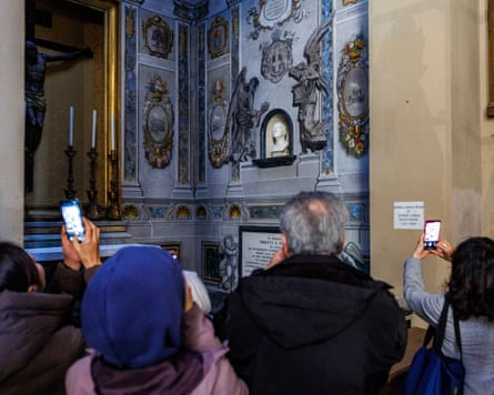 A group of people look at fresco in a church.