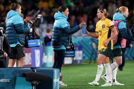 Australia's forward #20 Sam Kerr (C), ruled out due to injury, hands out water bottles to teammates at half time