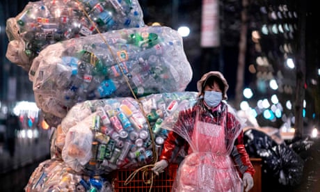 A woman pulls a cart loaded with bags of recyclables through the streets of New York City.
