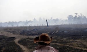 A farmer walks on a smouldering field after it was hit by a fire burning a tract of the Amazon forest in Rio Pardo, Rondonia, Brazil 16 September 2019.