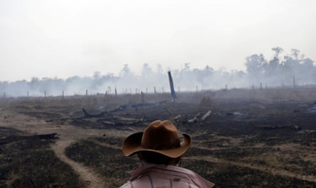A farmer walks on a smouldering field after it was hit by a fire burning a tract of the Amazon forest in Rio Pardo, Rondonia, Brazil 16 September 2019.