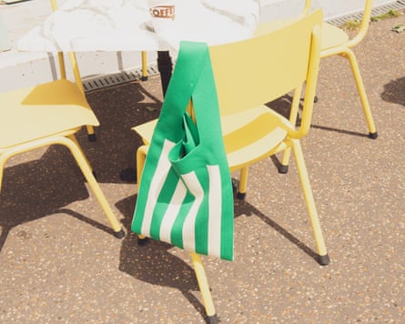 Striped green bag hanging on yellow outdoor chair