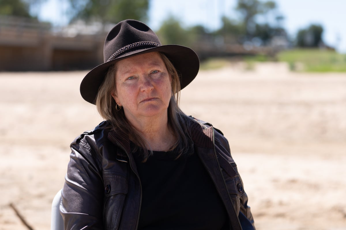 A woman in a wide brimmed brown hat and leather jacket on a deserted road