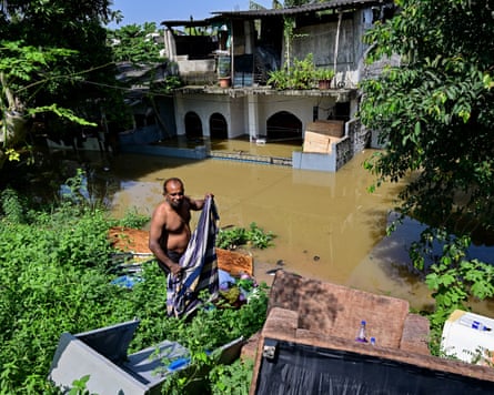 A man takes shelter at an elevated area outside his flooded house