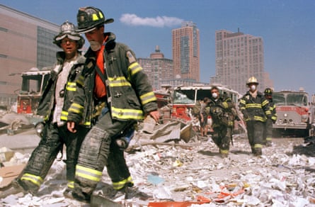 firefighters walk on top of rubble