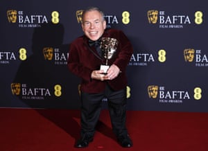Warwick Davis poses in the press room after winning the fellowship award