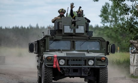 Ukrainian service members ride an armoured vehicle near the Ukraine-Russia border in the town of Vovchansk