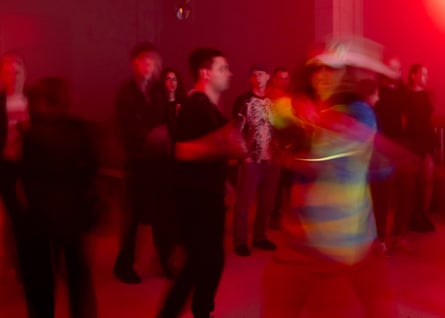 Blurry image of people dancing under red light
