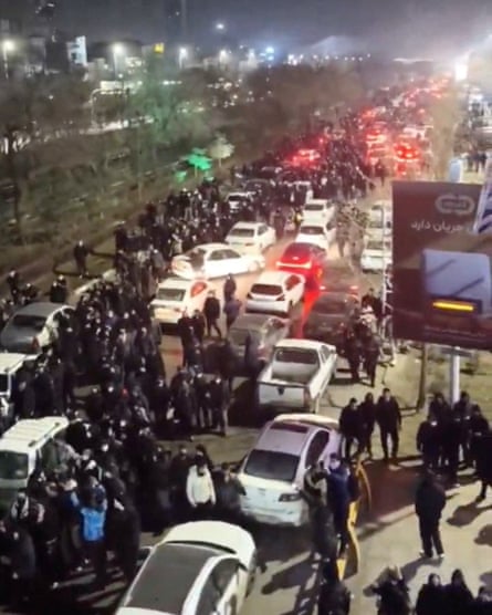 Screengrab showing people standing in the street among vehicles at night