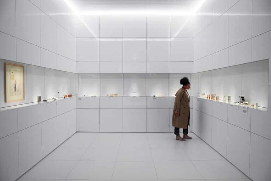 A woman inspects a collection of perfume and cosmetic bottles at Gabrielle Chanel: Fashion Manifesto.