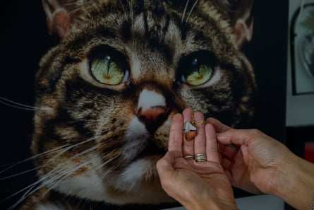person holds up necklace in front of picture of cat