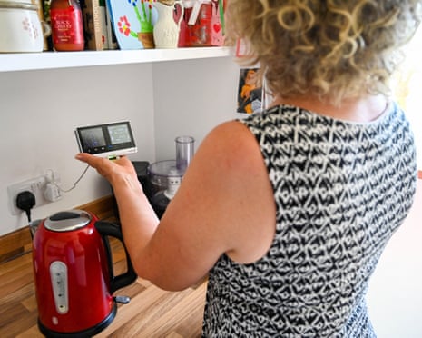 A woman looking at her British Gas smart meter in her kitchen.