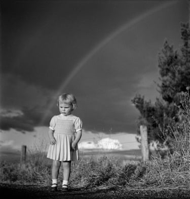 Black and white photograph of a very young girl with an approaching storm in the background behind her