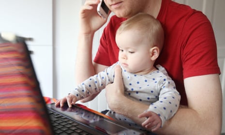 A father works from home on his laptop with a baby on his lap