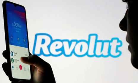 Woman holds smartphone with Revolut app in front of displayed Revolut logo