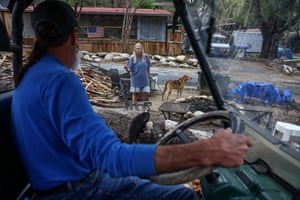 A man in a vehicle talks to a woman standing with a dog