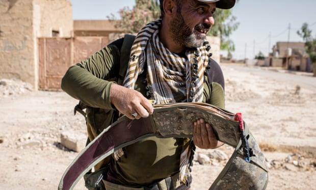 A member of the Asa’ib Ahl al-Haq militia carefully handles a seized Isis suicide belt found in Ba’aj, northern Iraq.