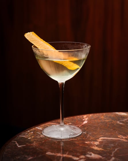 Dover martini with a strip of orange peel on a round marble tabletop
