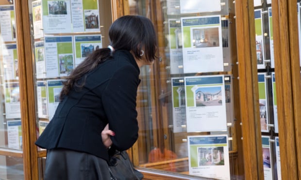 Young woman looking in estate agent's window