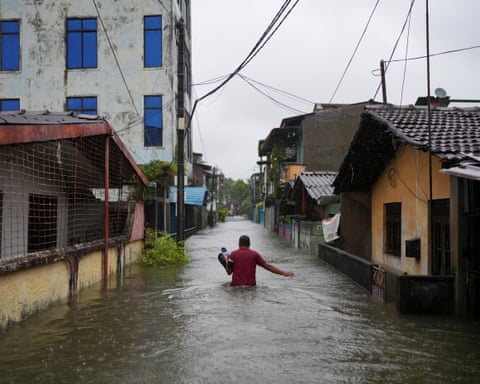 A man wades through a flooded street in Wellampitiya, Sri Lanka