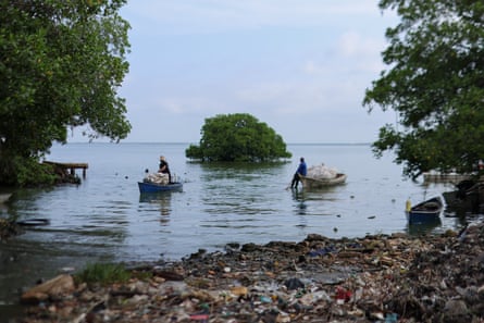 Fishers carry bags with plastic waste retrieved from the lake, in a mangrove.