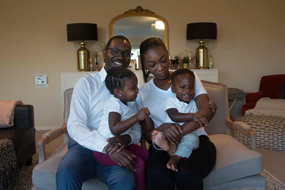 Robert and Ayooluwa hold daughter Forefulowa, 3, and son Folajimi, 1, on their laps at home in London