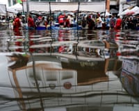 people shopping in a flooded market are reflected in the flood water