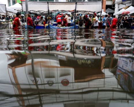 people shopping in a flooded market are reflected in the flood water