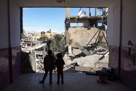 Two Palestinian children stand near rubble