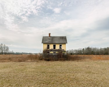 A simple yellow wooden house, its verandah roof gone, is slowly reclaimed by wild saplings