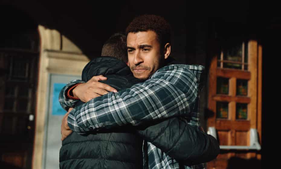 Two men huggingTwo men hug outside of a building