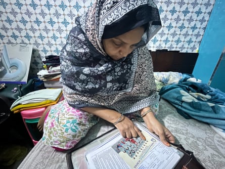 Shaheen’s mother, Sultana Khatoon, looks at her school photos and report cards.