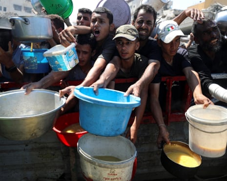 Palestinians gather to receive food from a charity kitchen, amid a hunger crisis, in Gaza City on 23 July 2025.